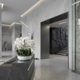 White phalaenopsis orchids in a low white bowl planter with stones on a modern gray reception desk