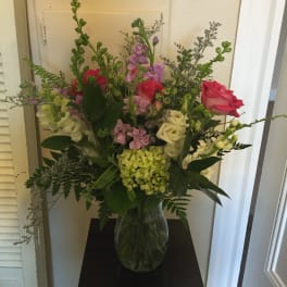 Mixed bouquet of pink, white, and purple flowers in a glass vase