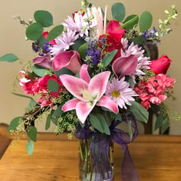 Mixed pink and purple bouquet in a glass vase with a ribbon