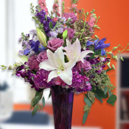 Purple and white floral arrangement in a tall vase