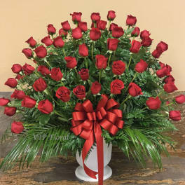 Large arrangement of red roses in a white urn with a red ribbon bow