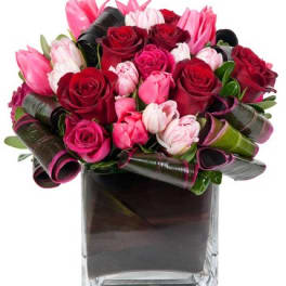 Bouquet of pink and red roses and tulips in a square glass vase