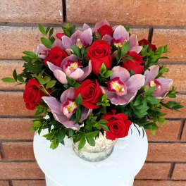 Bouquet of red roses and pink orchids in a silver vase