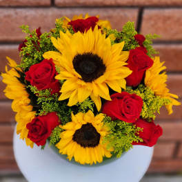 Bouquet of yellow sunflowers and red roses in a white vase