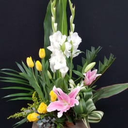Tall floral arrangement with pink lilies, white gladiolus, and yellow tulips