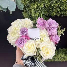 Heart-shaped bouquet of white, pink, and lavender roses with a striped ribbon