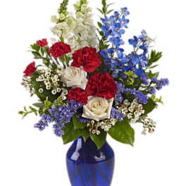 Mixed bouquet of red, white, and blue flowers in a cobalt vase