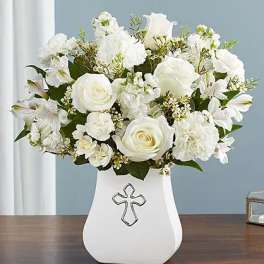 White floral arrangement in a vase with a cross emblem