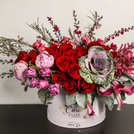 Red and pink roses with purple blooms in a round hat box