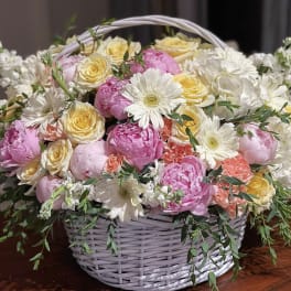 Basket of pink and yellow roses with white daisies
