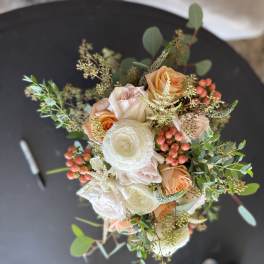 Bouquet of peach and white roses with berries and greenery