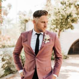 Man in a mauve suit wearing a boutonniere