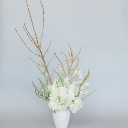 White floral arrangement in a textured white vase with tall branches