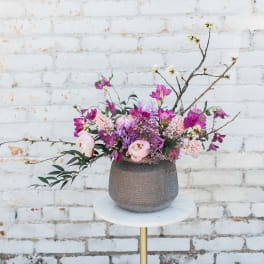 Pink and purple floral arrangement in a textured vase