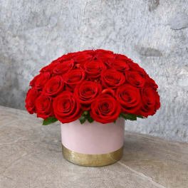 Round bouquet of red roses in a pink and gold box