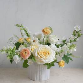 White and peach roses arranged in a white vase