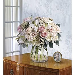Pink and white roses with lilies in a clear glass vase on a table