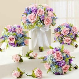 Pink rose bouquets with blue and purple flowers on white stands