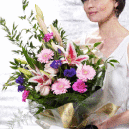 Woman holding a mixed bouquet of pink, purple, and white flowers