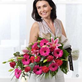 Woman holding a large bouquet of pink flowers wrapped in paper
