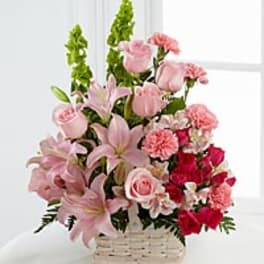 Pink and red floral arrangement in a white basket