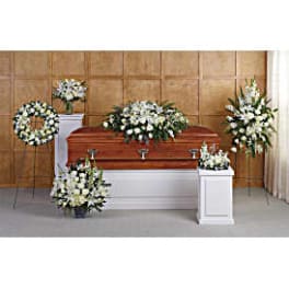 White funeral casket surrounded by white floral sprays and wreaths