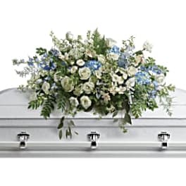 White and blue floral casket spray on a silver casket
