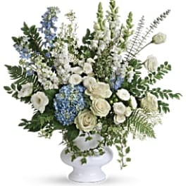 White and blue floral arrangement in a white pedestal vase