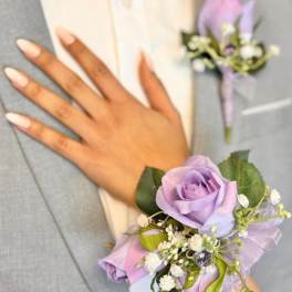 Lavender rose corsage with small white flowers on a wrist