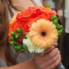 Handheld bouquet of orange roses, a peach gerbera daisy, and white carnations