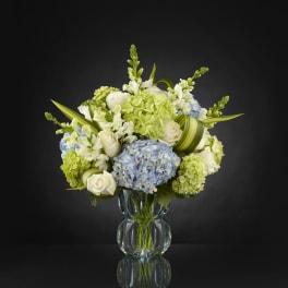 Blue and white floral arrangement in a clear glass vase