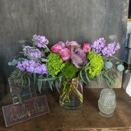 Bouquet of pink roses and purple flowers in a glass vase
