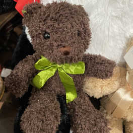 Brown teddy bear with a green ribbon, shown with other plush toys
