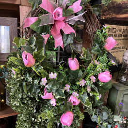 Pink tulips and ivy arranged on a grapevine wreath with a ribbon bow