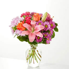 Mixed pink and orange flowers in a clear glass vase