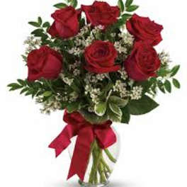 Bouquet of red roses with baby's breath in a glass vase tied with a red ribbon