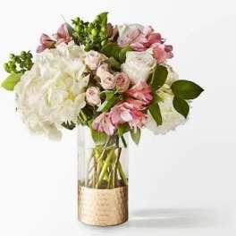 Pink and white bouquet in a clear glass vase with a gold wrap