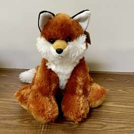 Plush fox toy sitting on a wooden floor