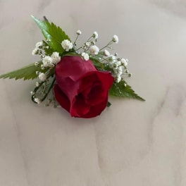 Red rose boutonniere with baby's breath and green leaves