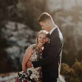Couple embracing, with the woman holding a bouquet of pink and white flowers