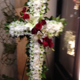 White floral cross with red roses on a stand
