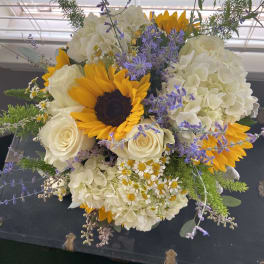 Bouquet of sunflowers, white roses, and white hydrangeas with purple accents