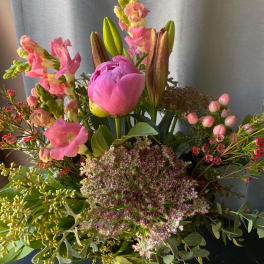 Mixed bouquet with pink peonies, lilies, and snapdragons in a glass vase