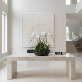 White orchid arrangement in a black bowl on a marble table