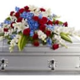 Red, white, and blue floral spray on a white casket