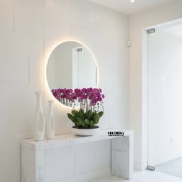 Purple orchids in a white bowl on a marble console table