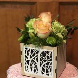 Small floral arrangement with peach roses in a decorative wooden box