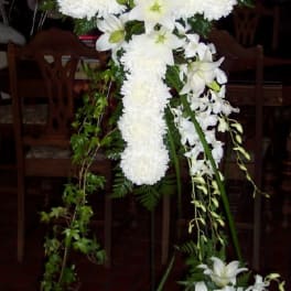 White floral cross arrangement with lilies and pompons on a stand