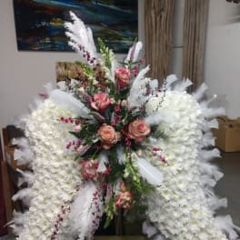 Large white floral standing spray with pink roses and white feathers