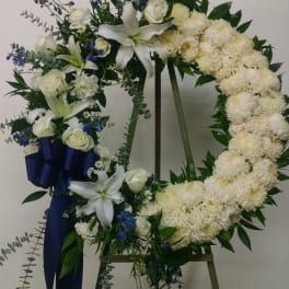 White floral wreath on an easel with blue ribbon accents
